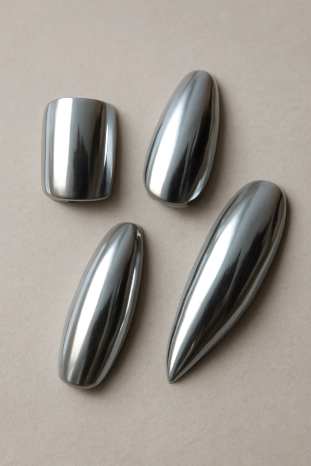 Flat lay of chrome nails in different shapes including square, almond, stiletto, coffin