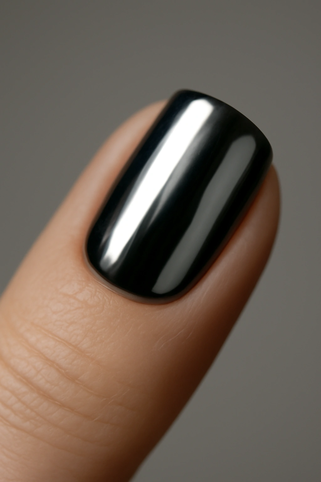 Close-up of a black-based nail with chrome powder finish