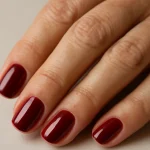Close-up of hand nails painted in deep burgundy red with glossy finish