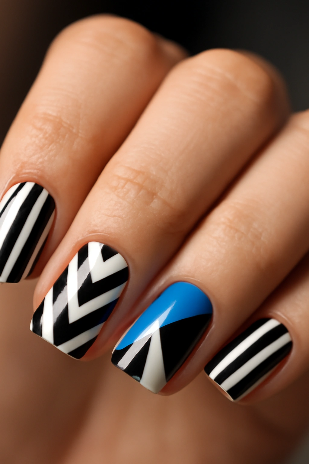 Square nails with bold geometric patterns in black, white, and blue