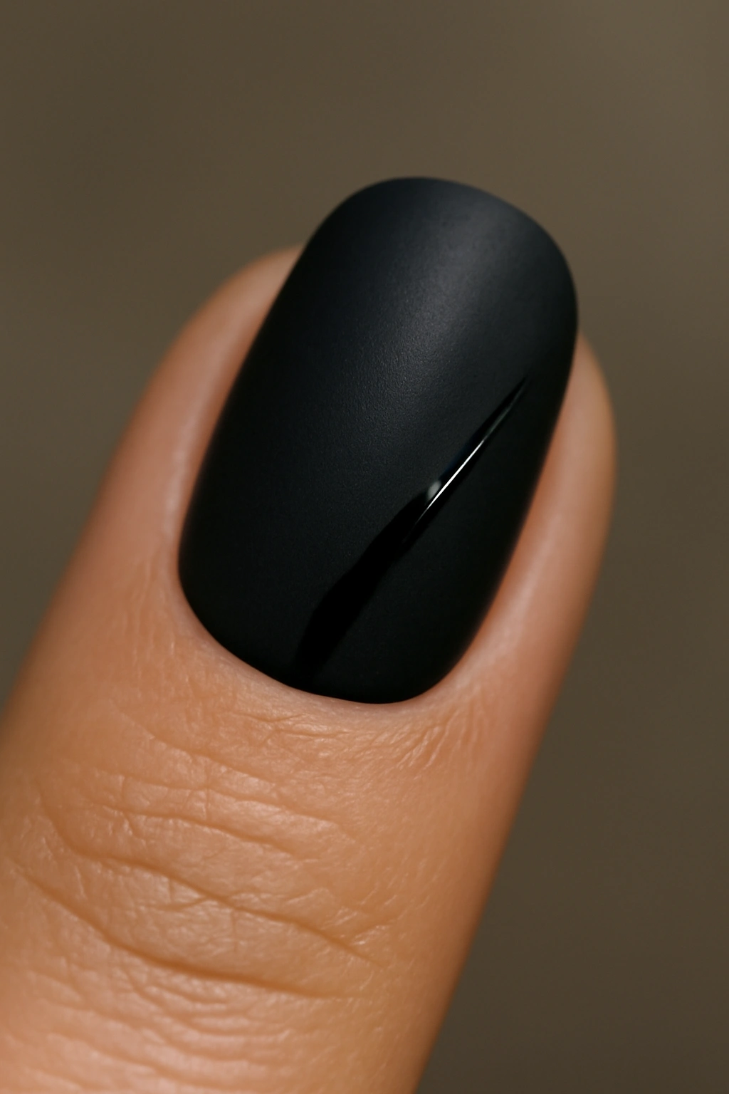 Close-up of a fingernail with matte black finish and glossy accent