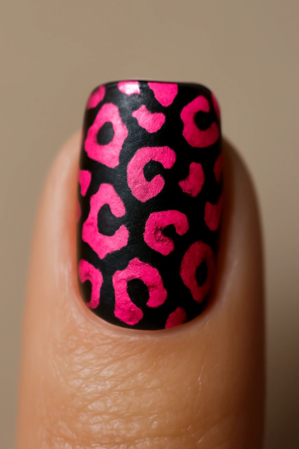 Close-up of a nail with neon pink leopard print on a dark base