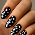 Close-up of black nails with white polka dots in a monochrome manicure
