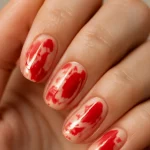 Close-up of red abstract nail art on hand