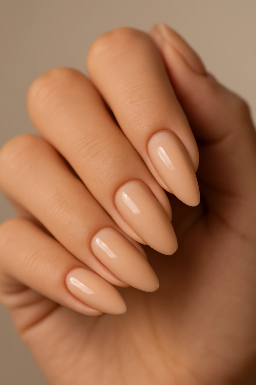 Close-up of almond-shaped nude nails on a clean background