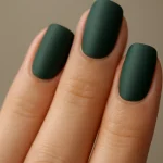 Close-up of forest green nails on a hand with matte finish