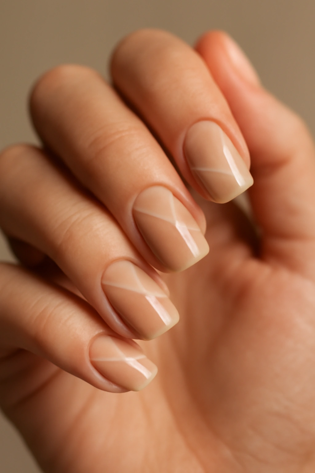 Close-up of nude nails showing negative space geometric patterns