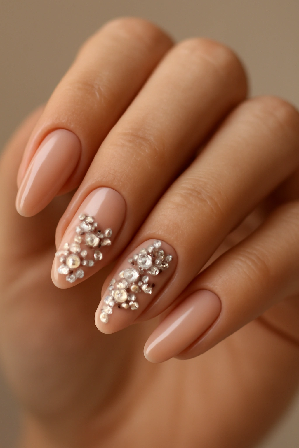 Close-up of nude nails with rhinestone accents sparkling